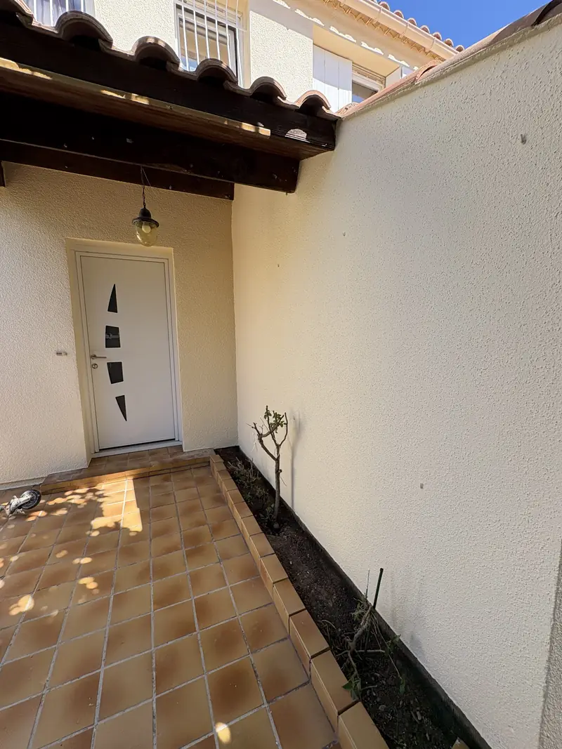 Entrée de maison à Béziers — murs crépis repeints autour de la porte d'entrée blanche