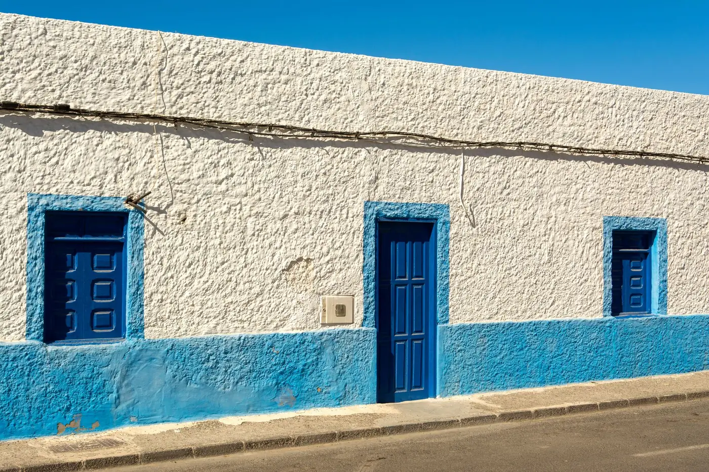 Façade de maison peinte en blanc et bleu sous le soleil méditerranéen